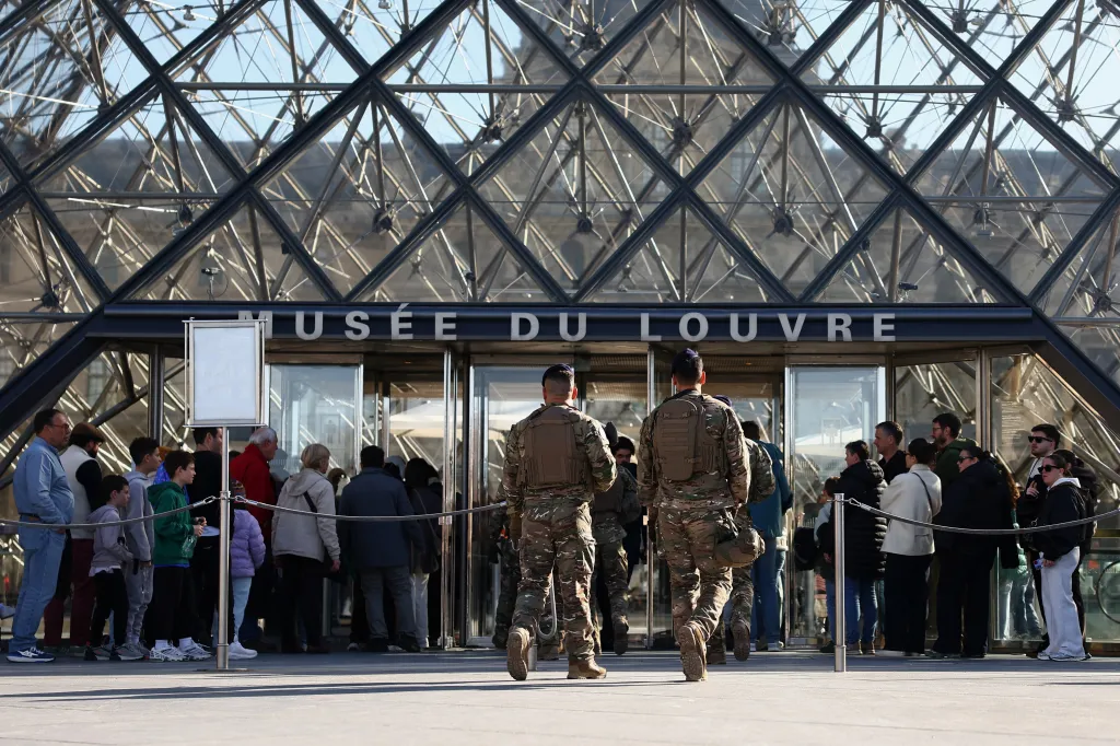 French soldiers from the Sentinelle security plan patrol past the glass Pyramid at the Louvre Museum in Paris, France.
