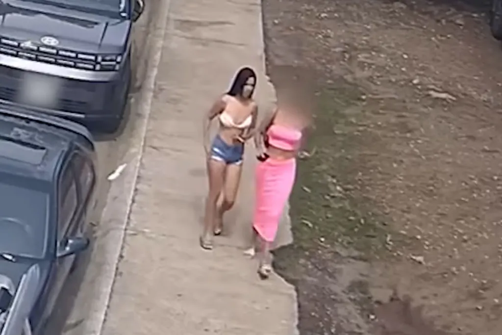 Surveillance footage of two women walking along a sidewalk next to parked cars in Playas del Coco.